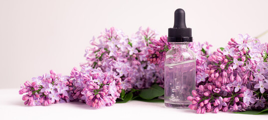 Obraz na płótnie Canvas Hyaluronic acid bottle and lilac on a white background . Beauty container. Skin care. Vitamins for the skin. Rejuvenation. Female beauty. An article about the benefits of hyaluronic acid. Article abou