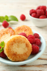 Delicious cottage cheese pancakes with raspberries on white wooden table, closeup
