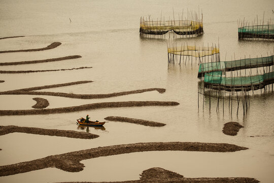 A boat sailing across Xiapu's mudflats at low tide