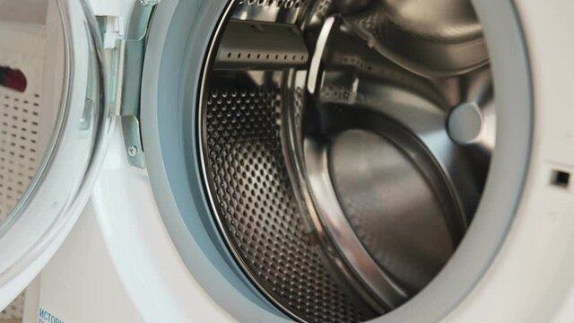 Washing machine laundry. Woman housewife puts different dirty socks into grey shining automatic machine under bright electric light close view