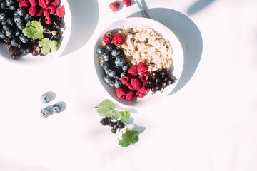 Oatmeal with raspberries and blueberries in a white plate .Breakfast