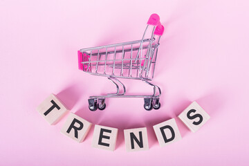 TERNDS - word on wooden cubes, on a pink background with a shopping trolley.
