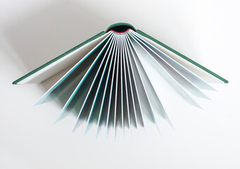 Open photobook with thick plastic sheets in a hard green cover on the background of a wooden table....