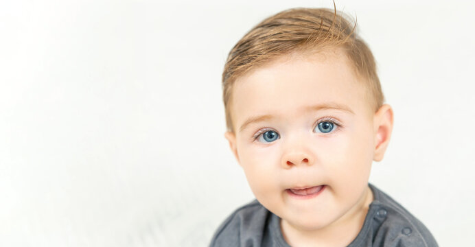 Headshot portrait of adorable smiling baby boy, shows tongue. Copy space, white background