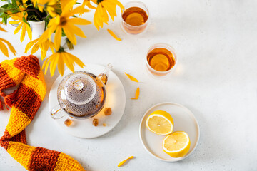 Obraz na płótnie Canvas Beautiful autumn composition with knitted scarf, hot teapot, two cups of tea and yellow flowers bouquet. Autumn still life with tea. Fall, hygge, menu, greeting card concept. Copy space