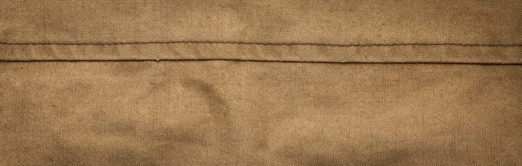 Wide panoramic surface texture of army rough khaki fabric with seam and dark vignette. Template for...