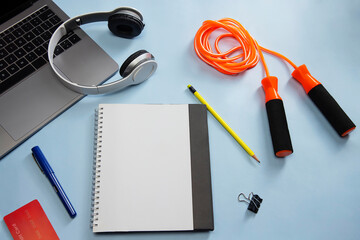 A notepad,skipping rope,pencil,pen,headphones, laptop,paper-clip and credit card kept together.