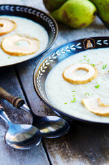A creamy fall season soup with pears and celery root, garnished with dried apple rings.
