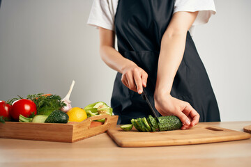 housewife in a black apron in the kitchen cooking vitamins salad