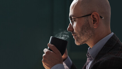 Bald man holding a mug of hot drink and sniffing it - Powered by Adobe