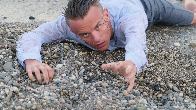 Exhausted man on the seashore asks for help stretching out his hand