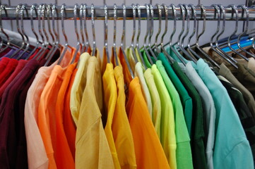 Colorful clothes on hangers in wardrobe