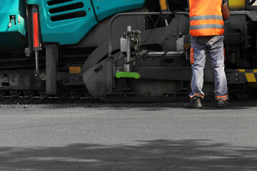 Fototapeta premium Worker working with asphalt finisher on city street, closeup. Road repair service