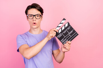 Portrait of attractive amazed guy filmmaker assistant using board producing movie isolated over pink pastel color background
