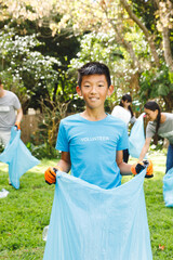 Portrait of smiling asian son, collecting rubbish in sacks with family in the countryside