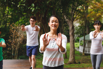Happy asian parents, son and daughter exercising outdoors, practicing tai chi