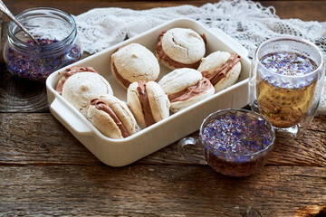 Almond cookies with chocolate cream. Cornflower blue tea, wood background, side view.