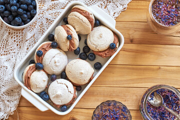 Almond cookies with chocolate cream. Blueberries, cornflower blue tea, wood background, side view.