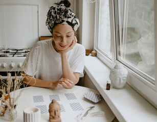 woman with tarot cards on the white kitchen - obrazy, fototapety, plakaty