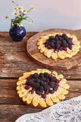 blackberry flower pie on a wooden table. Flowers, coffee, shortcrust pastry, ricotta, ice cream, chamomile, side view.