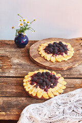 blackberry flower pie on a wooden table. Flowers, coffee, shortcrust pastry, ricotta, ice cream, chamomile, side view.