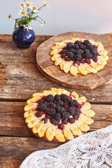 blackberry flower pie on a wooden table. Flowers, coffee, shortcrust pastry, ricotta, ice cream, chamomile, side view.