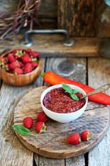 raspberry sauce with chili. Wooden background, side view.