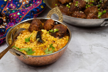 Vegan Indian Lentil Dal with vegan koftas in traditional bowl on marble table