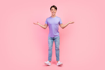 Full length body size view of attractive cheerful funny guy having fun holding copy space isolated over pink pastel color background