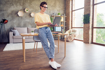 Full length body size view of attractive cheerful girl using laptop programming finance plan at home loft industrial interior indoors