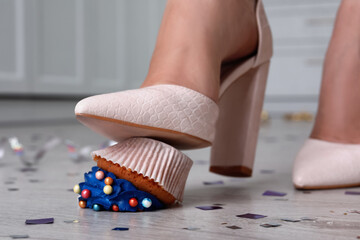 Woman stepping on dropped cupcake indoors, closeup. Troubles happen