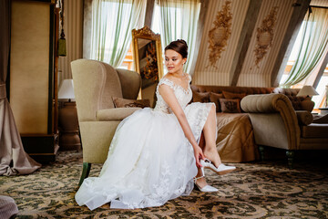 a beautiful bride in a white dress puts on shoes. wedding fashion. 