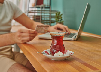 Close up Turkish tea on the wooden working desk, credit card and laptop style.