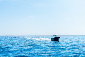 Small open black fishing boat with center console in motion in the early morning in the Atlantic Ocean