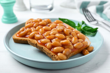 Toasts with delicious canned beans on white wooden table, closeup