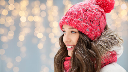 people, season and christmas concept - portrait of happy smiling teenage girl or young woman in winter over festive lights background