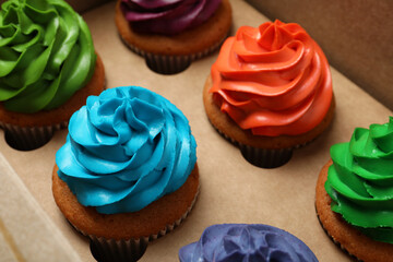 Different cupcakes with cream in box, closeup