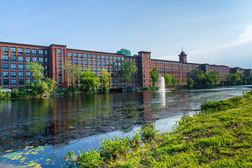 A heritage cotton mill building with a clock tower in the old industrial park of Nashua. Nashua Corporation. Nashua Manufacturing Company, New Hampshire, USA