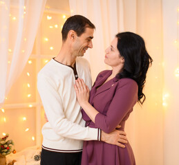 portrait of adult couple in home interior decorated with lights