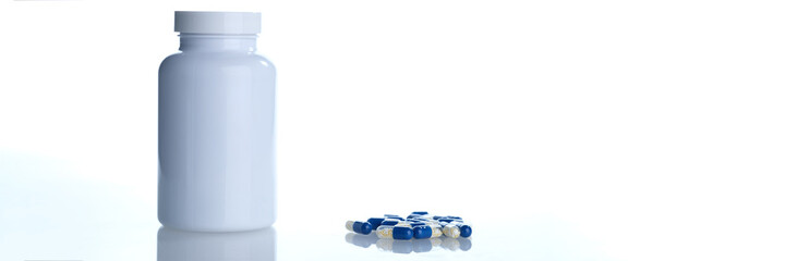 White blue pill capsules spilled from container of white plastic bottle