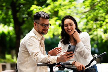 Happy funny couple with bicycle in the park. Loving couple enjoying together outdoors