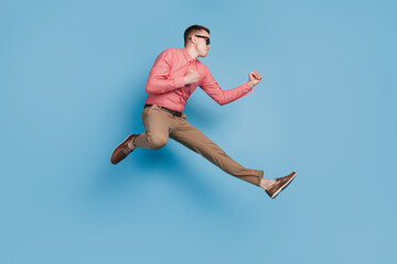 Fototapeta na wymiar Portrait of crazy fighter guy jump raise fists punch air on blue background
