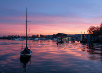 Exciting winter sunset on Lake Maggiore with sailboat in the foreground.Arona, Piedmont, Italy.