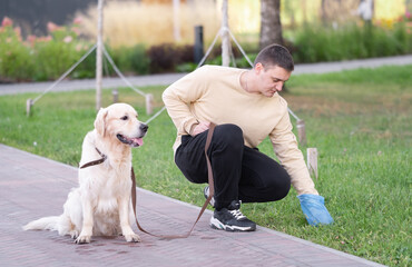 A man collects dog droppings, throws it into the trash can, keeping nature clean