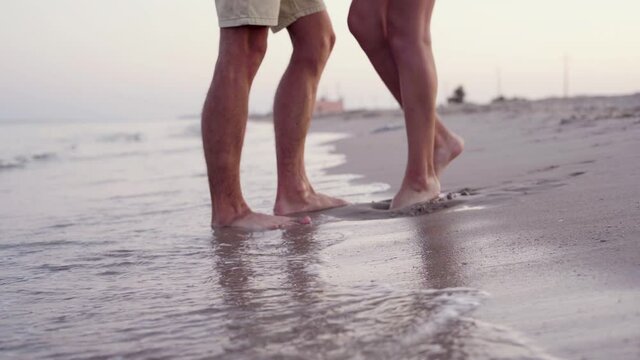 Close up of feet on the beach. A loving young couple hugs and kisses on the sand, selective focus.