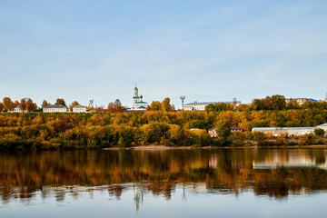 Natural view of the landscape with a lake or river and a city on the other side on the yellow shore in autumn day with blue sky