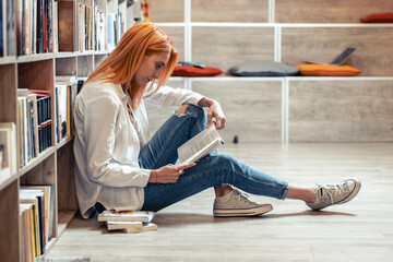 A red-haired female student sits alone in the library, engrossed in her book, studying with determination, eager to expand her knowledge and succeed in her academic pursuits.