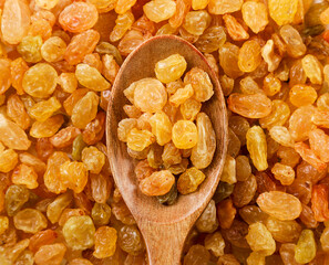 Yellow raisins in a wooden spoon background. Top view