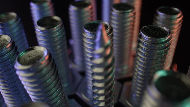 Rows of long bolts and nails on a table with a dark surface. Shiny metal, steel parts for household needs, top view. High quality. 4k footage.