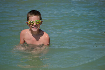 joyful boy with diving goggles in the water. happy childhood concept,